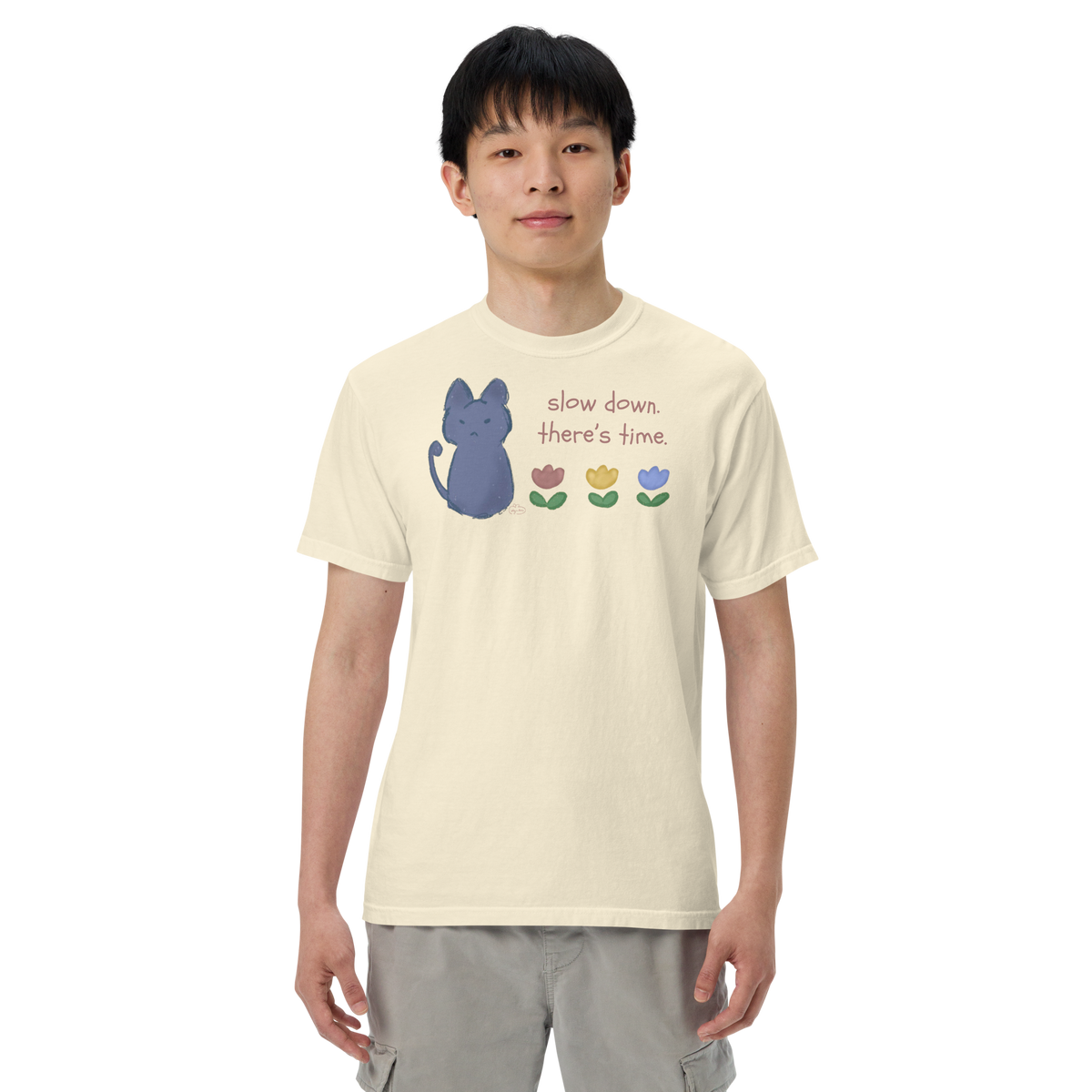 Model wearing a ivory Comfort Colors T-shirt with a blue cat, three flowers, and 'Slow down, there's time' lettering.