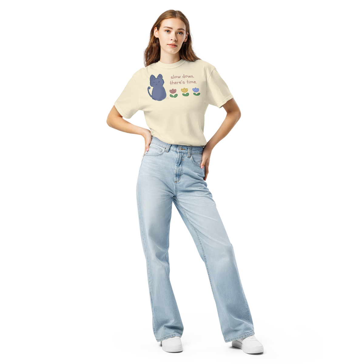 Model wearing a ivory Comfort Colors T-shirt with a blue cat, three flowers, and 'Slow down, there's time' lettering.
