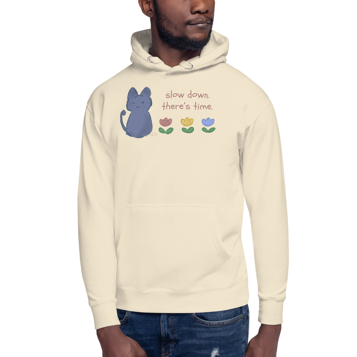 Model wearing a bone cream pullover hoodie with a blue cat, three flowers, and 'Slow down, there's time' lettering.
