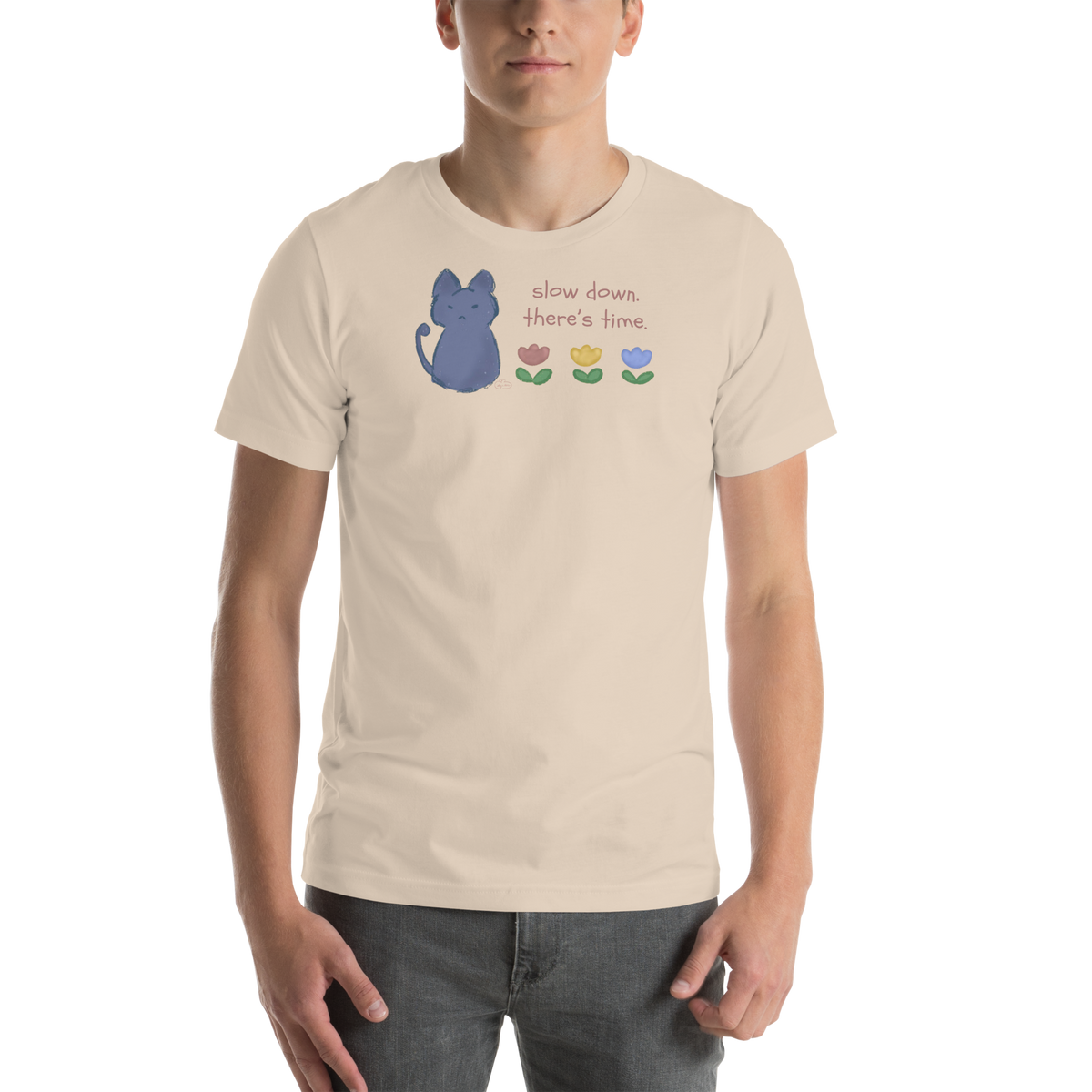 Model wearing a soft cream Bella + Canvas T-shirt with a blue cat, three flowers, and 'Slow down, there's time' lettering.